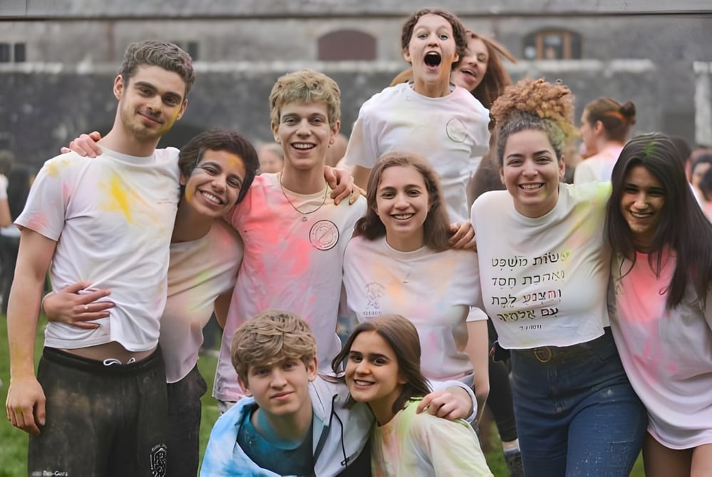 Eine Gruppe von Schülerinnen und Schülern steht gemeinsam auf einer Wiese vor einem Gebäude auf dem Campus des UWC Atlantic College.