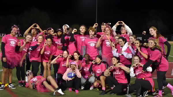 Eine große Gruppe junger Frauen in einheitlichen pinken Shirts steht draußen bei Nacht auf dem Gelände der Vacaville Christian School zusammen.