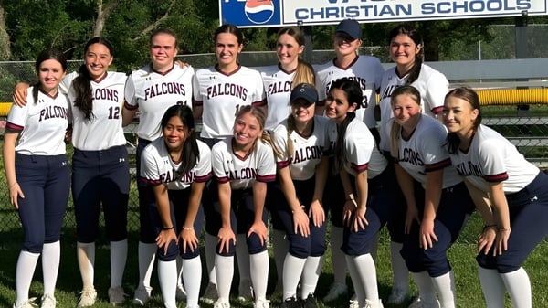 Eine Gruppe von Schülerinnen der Vacaville Christian School posiert in ihren Softball-Uniformen vor dem Schulschild.