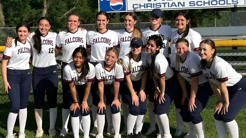Eine Gruppe von Schülerinnen der Vacaville Christian School posiert in ihren Softball-Uniformen vor dem Schulschild.