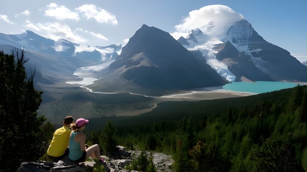 Zwei Personen sitzen auf einem Felsen und genießen die Berglandschaft mit See nahe der Valemount Secondary School.