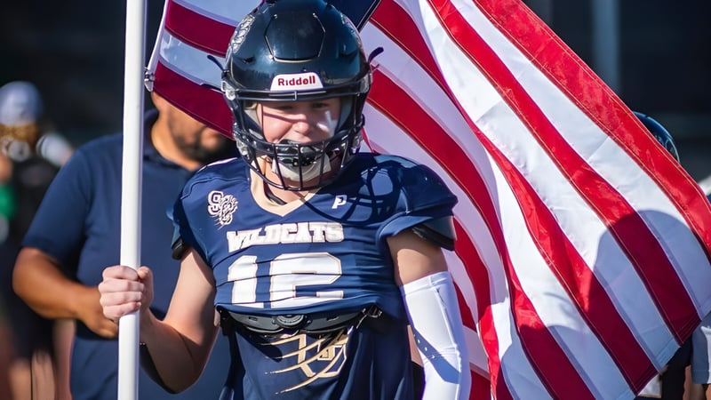 Ein Footballspieler der Valencia High School hält eine amerikanische Flagge vor einer Stadionkulisse.