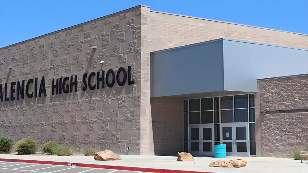 Das große Backsteingebäude der Valencia High School mit deutlich sichtbarem Schriftzug an der Fassade vor blauem Himmel.