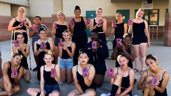 Eine Gruppe von Schülerinnen der Valencia High School posiert in einem Tanzstudio in verschiedenen Tanzkostümen.