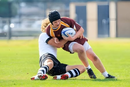 Zwei Rugbyspieler bei einem Tackle auf dem Spielfeld der Valley Christian High School.