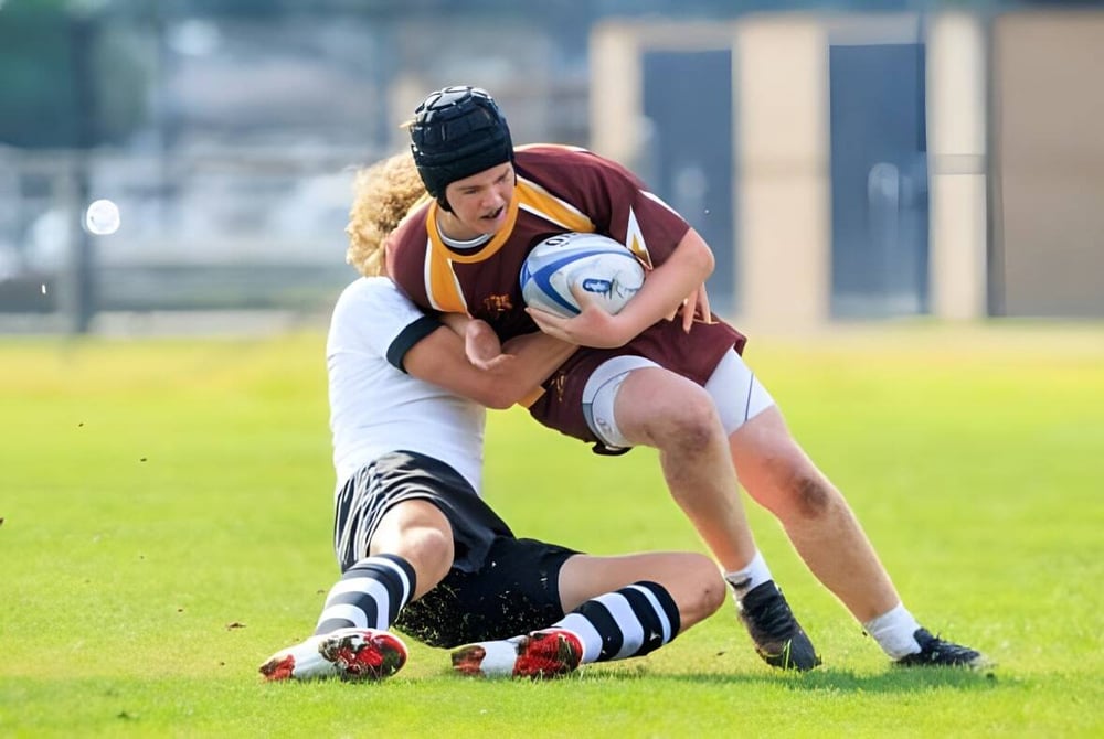 Zwei Rugbyspieler bei einem Tackle auf dem Spielfeld der Valley Christian High School.