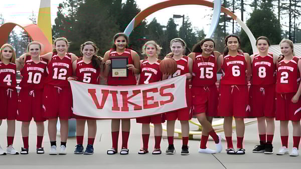 Eine Gruppe junger Athletinnen der Valley View Secondary hält ein Vikes Banner vor einem bunten Torbogen im Freien.