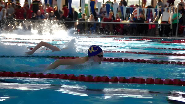 Eine Schwimmerin mit blauer Badekappe und Schwimmbrille beim Wettkampf im Schwimmbad des Vancouver Community College.