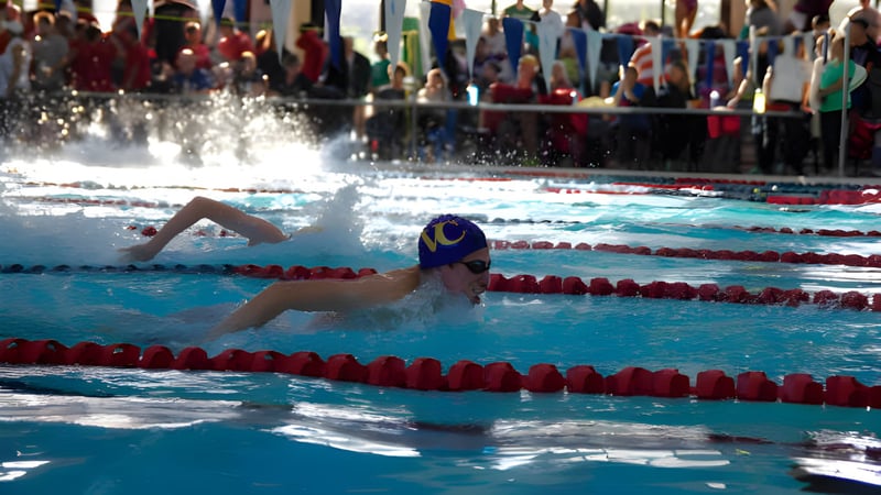 Eine Schwimmerin mit blauer Badekappe und Schwimmbrille beim Wettkampf im Schwimmbad des Vancouver Community College.