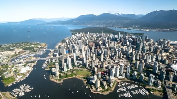 Blick auf die Skyline von Vancouver mit dem Hafen und Bergen im Hintergrund nahe dem Vancouver Community College.
