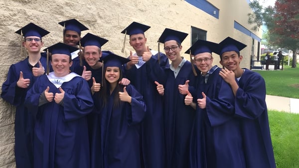 Eine Gruppe Absolventinnen und Absolventen der Vanguard School steht vor einem Backsteingebäude und zeigt Daumen hoch.