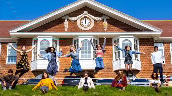 Eine Gruppe von Menschen steht vor dem historischen Gebäude mit Uhrturm auf dem Campus des Varndean College.