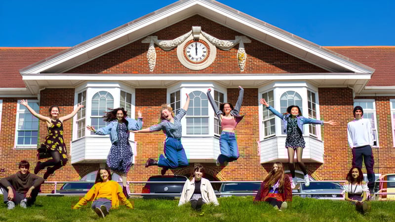 Eine Gruppe von Menschen steht vor dem historischen Gebäude mit Uhrturm auf dem Campus des Varndean College.