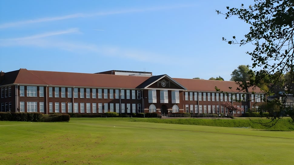 Das mehrstöckige Backsteingebäude mit rotem Dach auf dem Grünfeld am Varndean College.