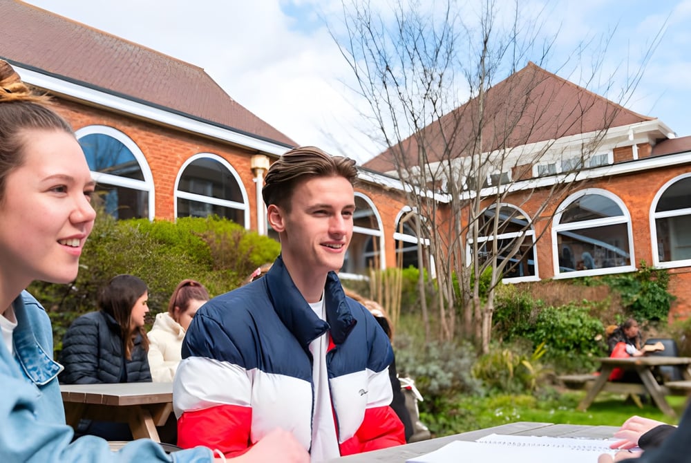 Schüler unterhalten sich an einem sonnigen Tag vor einem Backsteingebäude auf dem Campus des Varndean College.