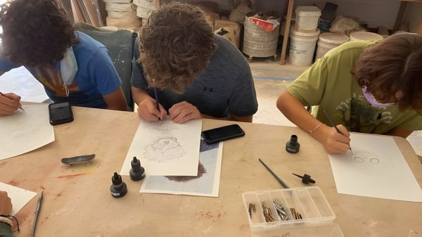 Schüler der Verde Valley School sitzen gemeinsam an einem Tisch und arbeiten an einer kreativen Zeichnungsaktivität.