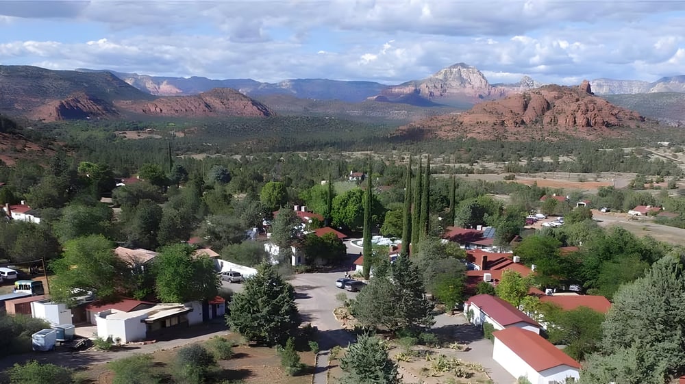 Die malerische Landschaft mit roten Felsen und grünen Wäldern nahe der Verde Valley School unter blauem Himmel.