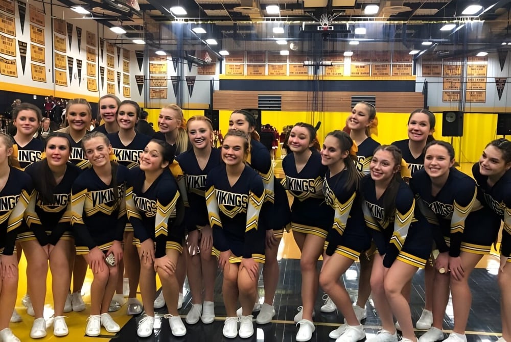 Eine Gruppe von Schülerinnen in Cheerleading-Uniformen steht in der Sporthalle der Vernon Township High School.