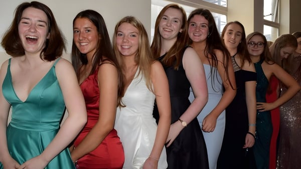 Eine Gruppe junger Frauen in formeller Kleidung posiert gemeinsam bei einer Feier am Victoria College Belfast.
