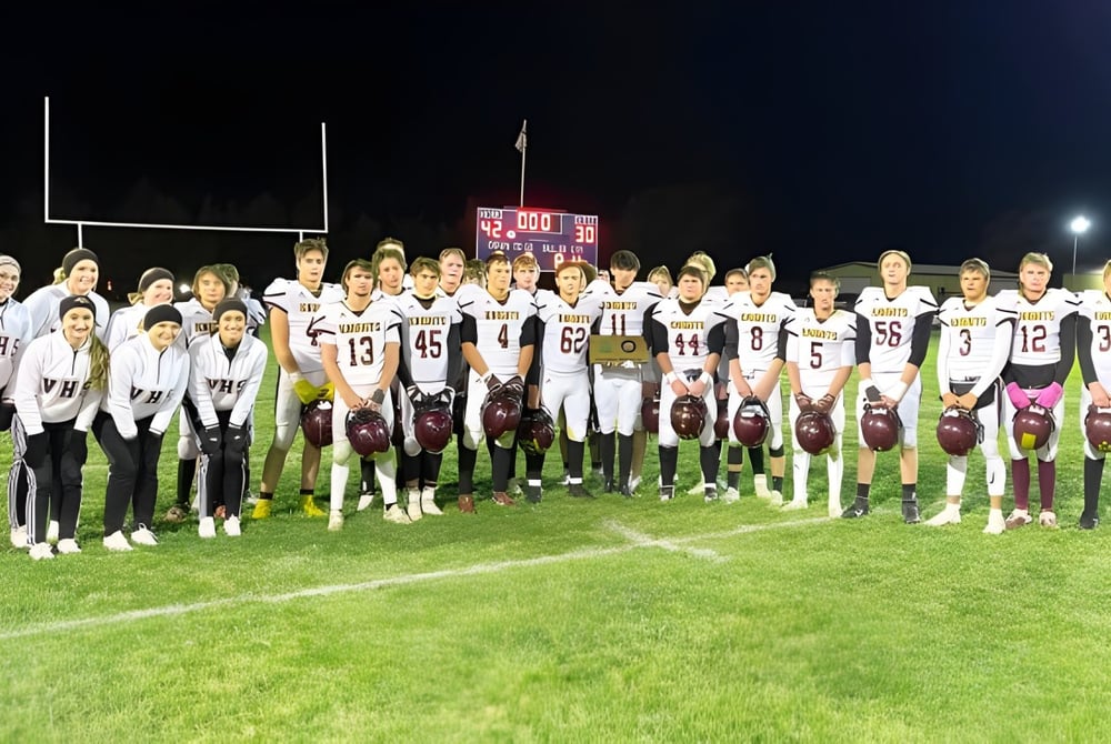 Eine Gruppe von Schülern der Victoria High School steht in weißen Trikots auf dem Fußballplatz bei Nacht.