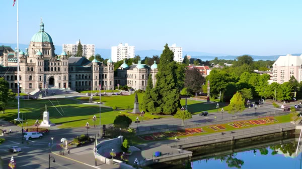 Ein historisches Regierungsgebäude mit grünem Dach in der Nähe von Victoria High School ist von Grünflächen und einem Kanal umgeben.