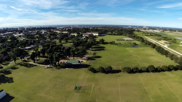 Ein großes grünes Feld mit vereinzelten Bäumen vor einer Stadtsilhouette ist nahe der Victoria Park High School zu sehen.