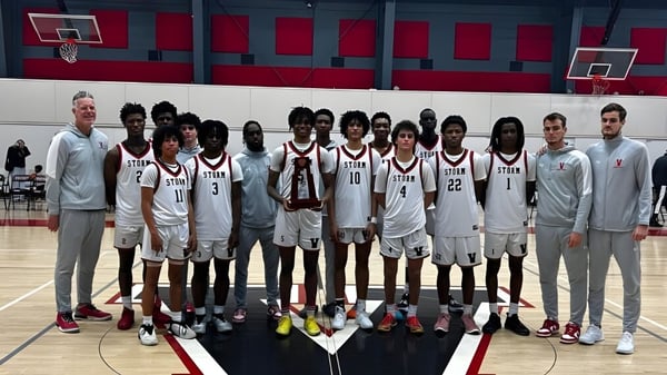Eine Gruppe von Basketballspielern posiert auf dem Basketballfeld der Victory Christian Academy vor roten und weißen Wänden.
