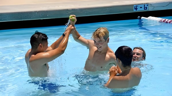 Schüler der Villanova Preparatory School planschen und spielen im Schwimmbecken mit Anzeigetafel im Hintergrund.
