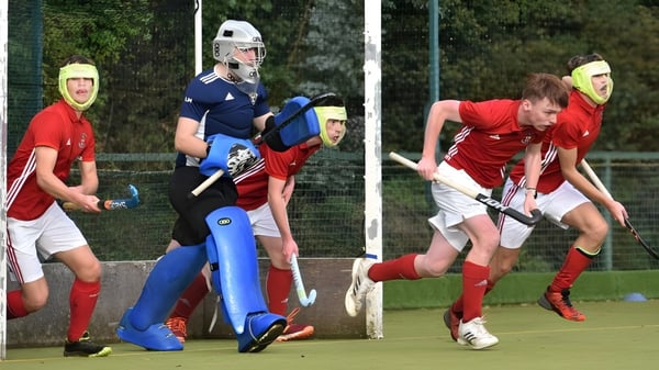 Schüler der Villiers School spielen ein Feldhockeyspiel auf einem Rasenplatz umgeben von Bäumen.