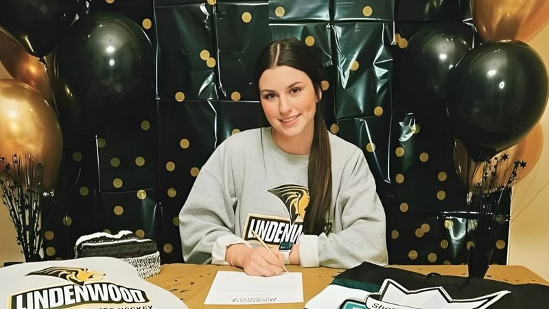 Eine Schülerin der Vimy Ridge Academy sitzt an einem Tisch mit schwarzen und goldenen Ballons im Hintergrund.