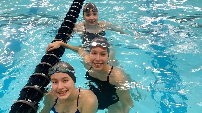 Drei Schülerinnen und Schüler schwimmen und haben Spaß im Pool auf dem Gelände der Vimy Ridge Academy.
