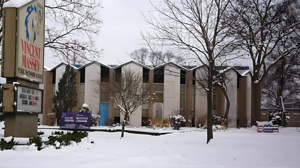 Schneebedeckte Landschaft mit mehrstöckigen Gebäuden und Schülern auf dem Campus der Vincent Massey Secondary School im Winter.