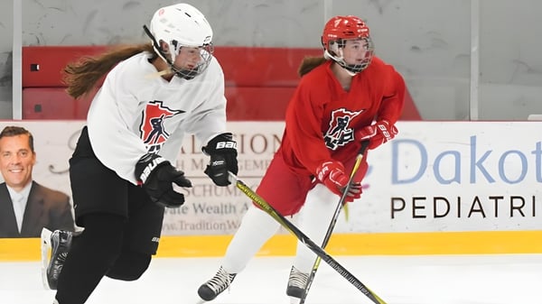 Zwei Hockeyspieler der Vineridge Academy in weißen und roten Trikots spielen auf dem Eisfeld.