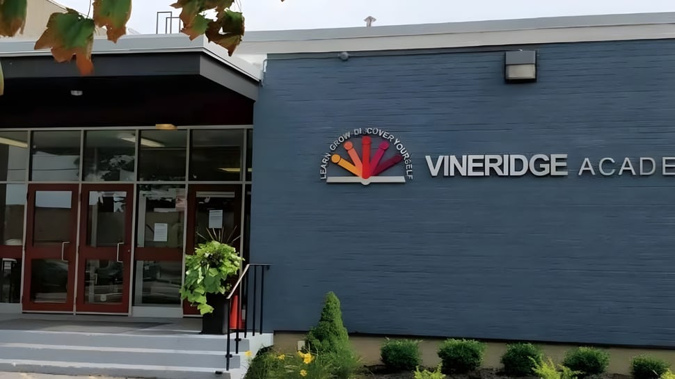 Das Gebäude der Vineridge Academy mit dunkelblauer Fassade und Pflanzen im Vordergrund.