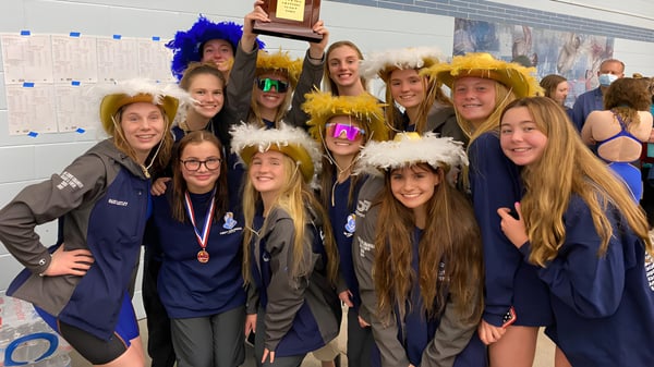 Eine Gruppe Schülerinnen des Virginia Beach City Public School District posiert in bunten Perücken und Kostümen vor Schulpostern.