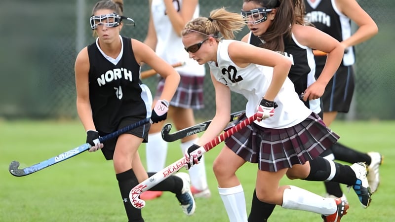 Eine Gruppe weiblicher Hockeyspielerinnen spielt ein Wettkampfspiel auf dem Feld des Virginia College.