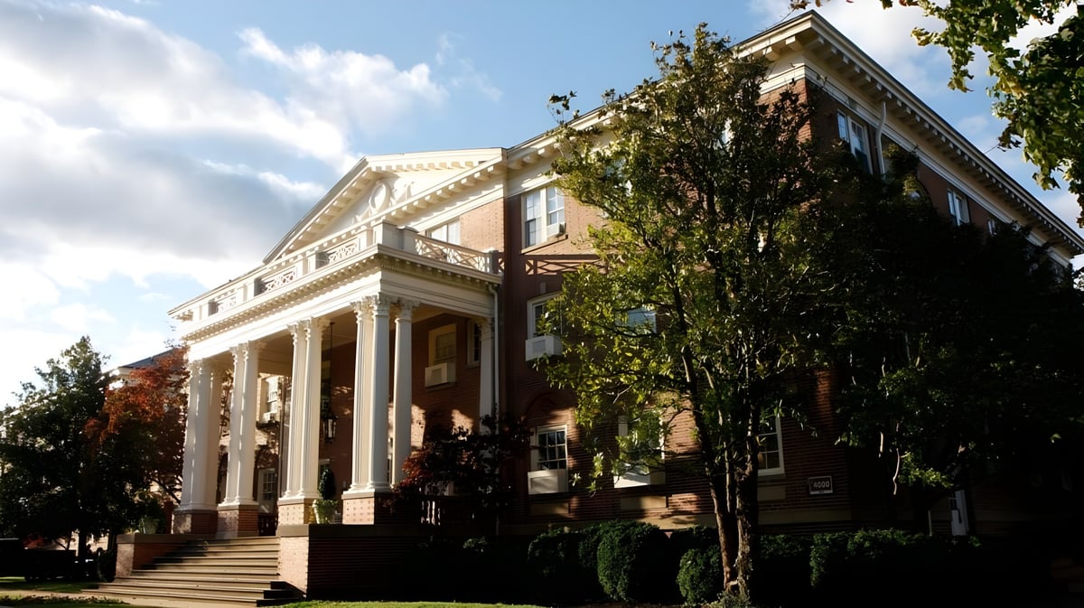 Das historische Hauptgebäude der Virginia Episcopal School mit Säulenfassade umgeben von grünen Bäumen unter blauem Himmel.