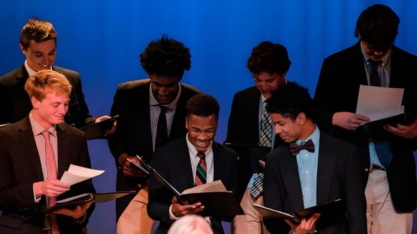 Eine Gruppe Männer in formeller Kleidung steht vor einem blauen Hintergrund auf der Virginia Episcopal School.