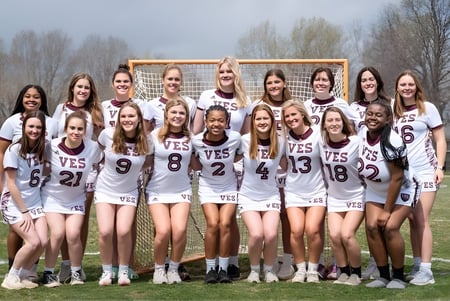 Eine Gruppe junger Schülerinnen in Sportuniformen steht zusammen auf dem Sportplatz der Virginia Episcopal School.
