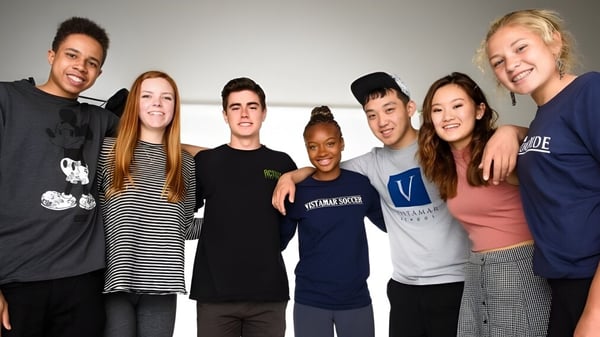 Eine Gruppe von Schülerinnen und Schülern der Vistamar School posiert lächelnd zusammen in einem lockeren Umfeld.