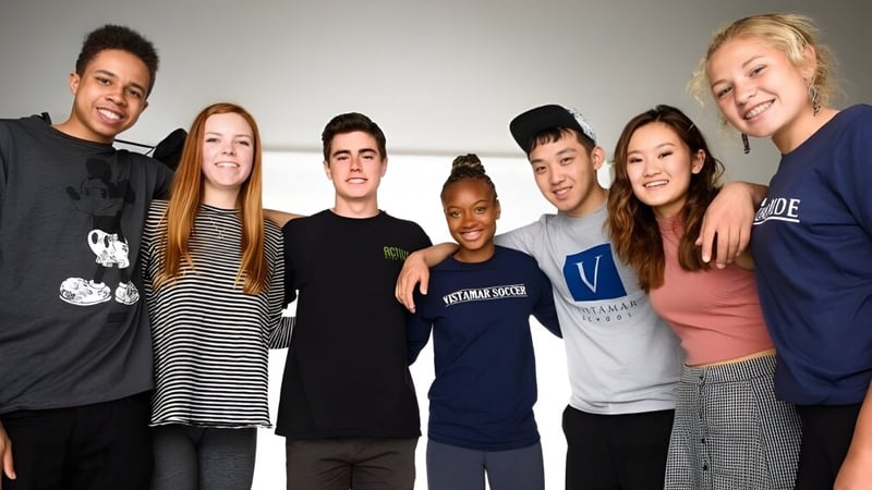 Eine Gruppe von Schülerinnen und Schülern der Vistamar School posiert lächelnd zusammen in einem lockeren Umfeld.