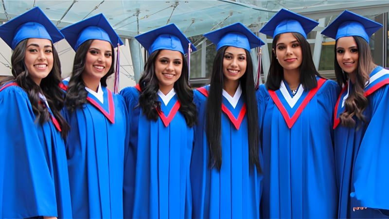 Eine Gruppe von Schülerinnen der W.P. Wagner High School feiert ihren Abschluss in blauen Talaren und Hüten.