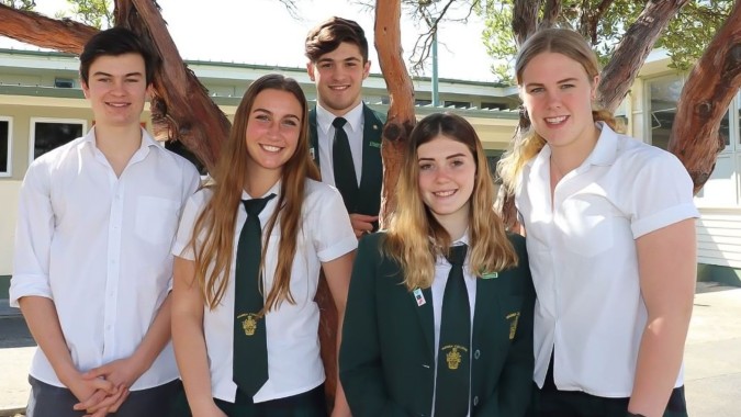 Eine Gruppe Schülerinnen und Schüler des Waimea College steht vor einem Gebäude mit Bäumen im Hintergrund.