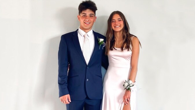 Ein junger Mann und eine junge Frau in formeller Kleidung stehen zusammen und lächeln in die Kamera auf dem Campus des Waimea College.