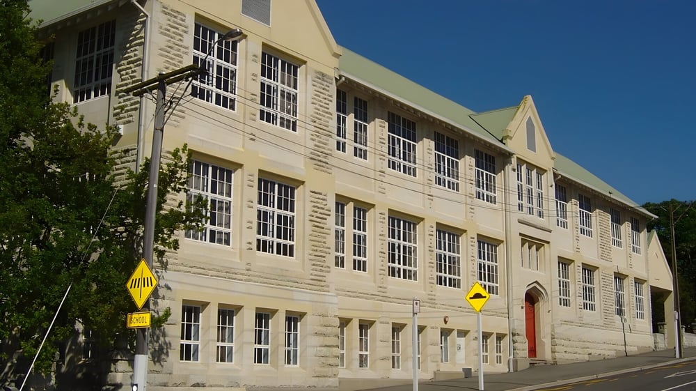 Das mehrstöckige Backsteingebäude mit großen Fenstern und roter Tür steht auf dem Gelände der Waitaki Girls’ High School.