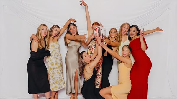 Eine Gruppe von Schülerinnen der Waitaki Girls’ High School posiert gemeinsam in bunten Kleidern vor einem weißen Hintergrund.