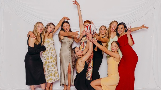 Eine Gruppe Schülerinnen der Waitaki Girls’ High School posiert vor weißem Hintergrund, einige heben dabei die Arme.