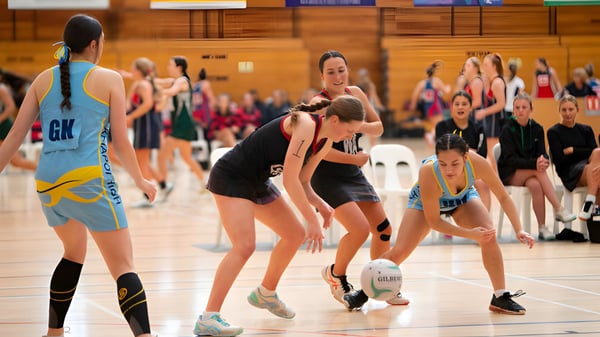 Schülerinnen der Waitaki Girls’ High School spielen ein Netballspiel auf dem Schulhof vor Zuschauern.