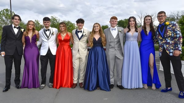 Eine Gruppe Schülerinnen und Schüler der Wakatipu High School posiert in formaler Kleidung im Freien vor Bäumen und bewölktem Himmel.