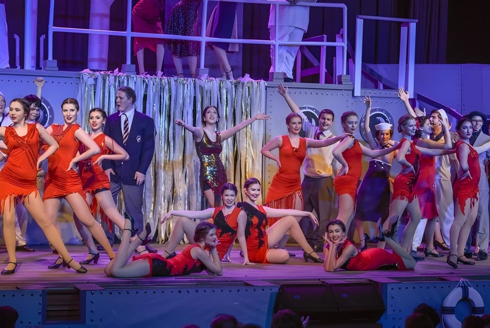 Schüler des Walkerville Collegiate Institute führen eine lebendige Tanzaufführung mit roten Kleidern auf einer farbenfrohen Bühne auf.